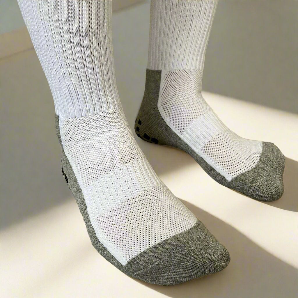 A pair of anti-slip compression socks worn on feet, featuring white upper fabric with mesh panel and gray non-slip grip at the sole.