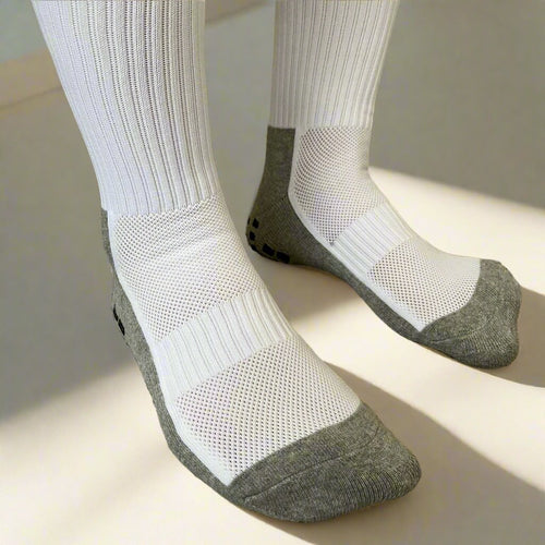 A pair of anti-slip compression socks worn on feet, featuring white upper fabric with mesh panel and gray non-slip grip at the sole.