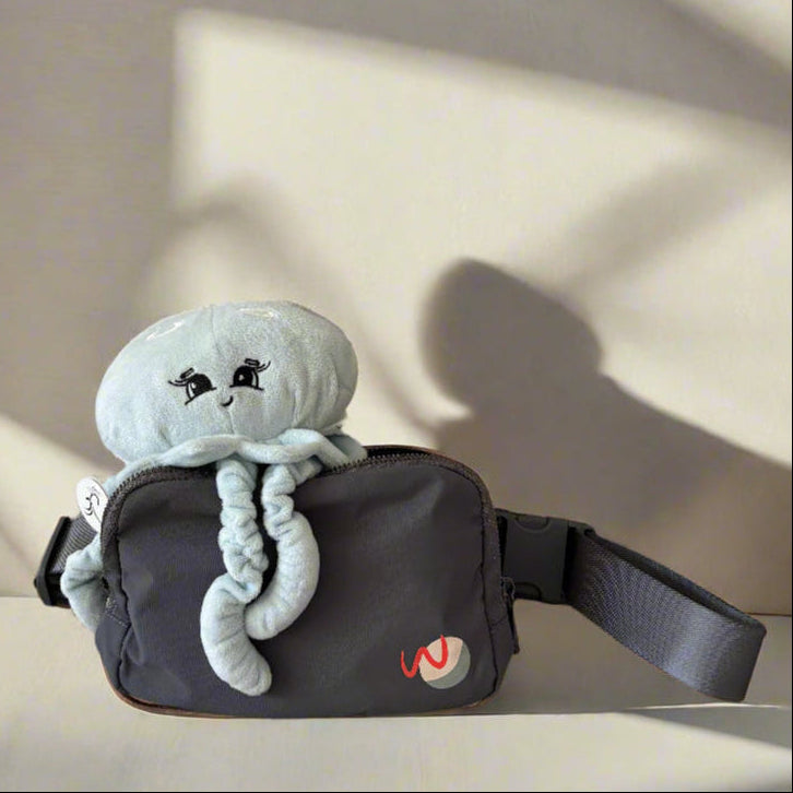 Light blue plush moon jellyfish in a black bag with a logo, against a neutral background