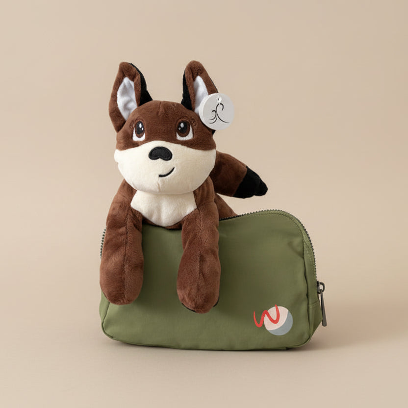 Plush fox stuffed animal sitting in green fanny bag