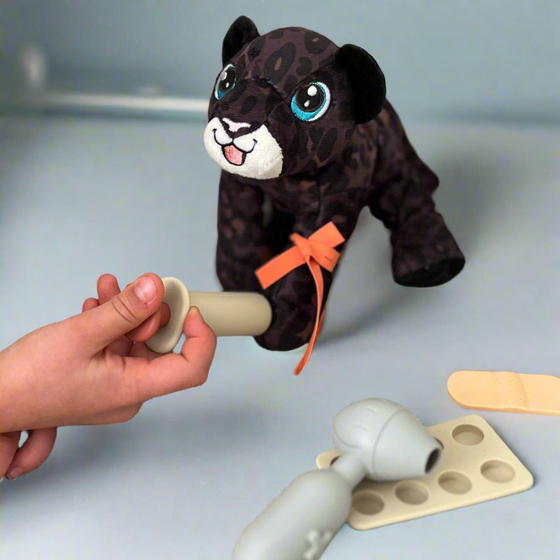 Plush black leopard toy being used to play with doctor play set